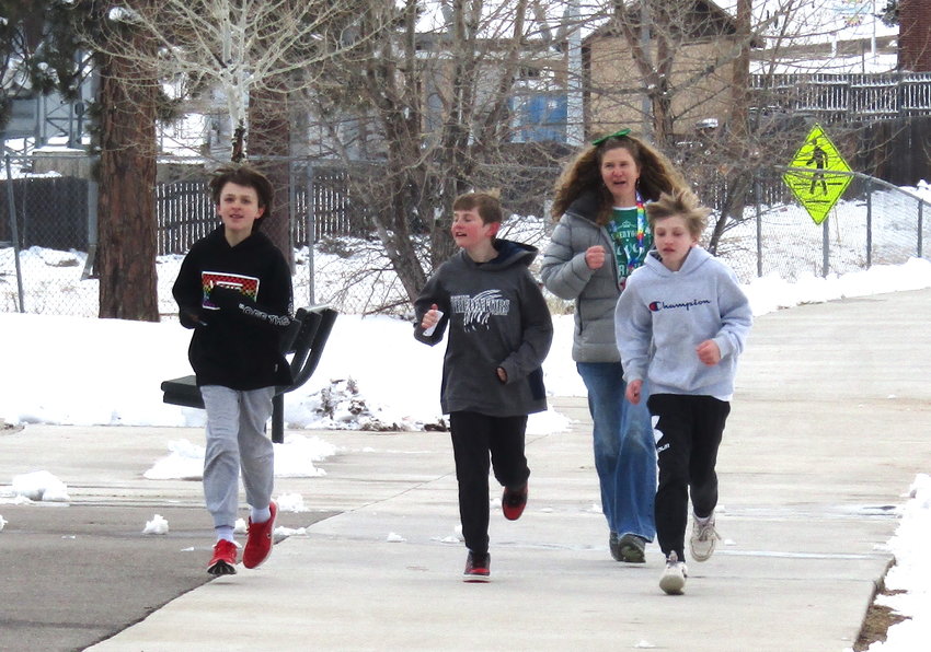 Cole Sargent, center, and his friends, Rhyder Vanni and Max Diesburg, along with 100 Mile Club coordinator Christine Olsen run the last lap around the West Jefferson Elementary School track so Cole could hit the 1,000-mile milestone.